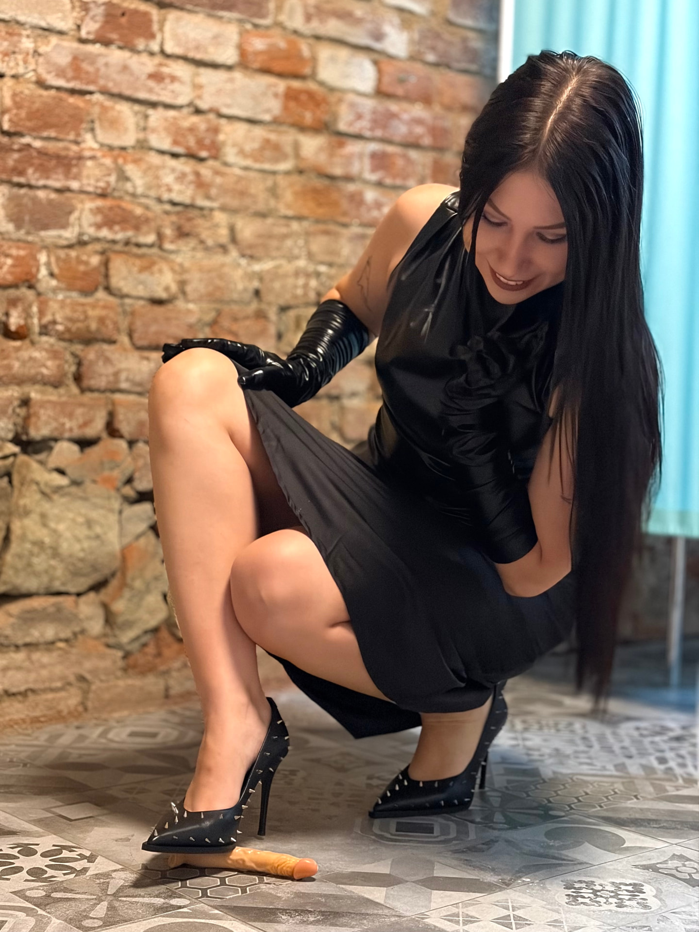 Lady Morgana crouching in latex gloves and spiked stiletto heels